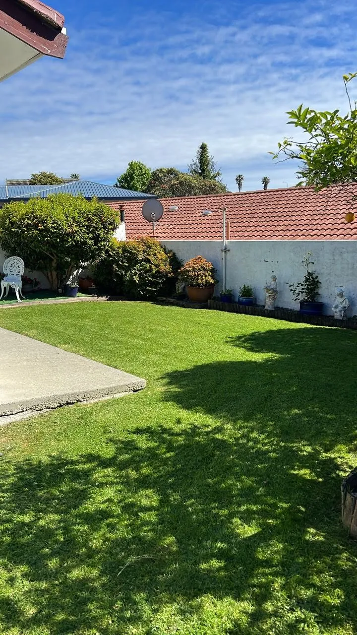 Neatly mowed lawn and tidied garden with potted plants