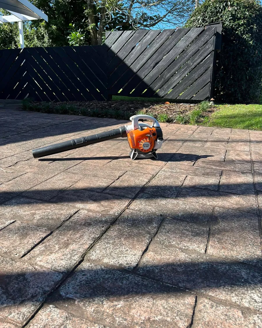 Blower on a clean paved patio beside a black fence