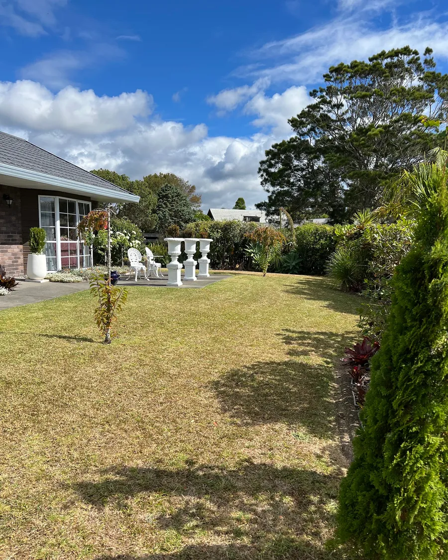 Mowed back lawn and tidy garden beds beside a brick house
